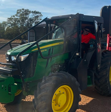 Green tractor operating in orchard during farming activities