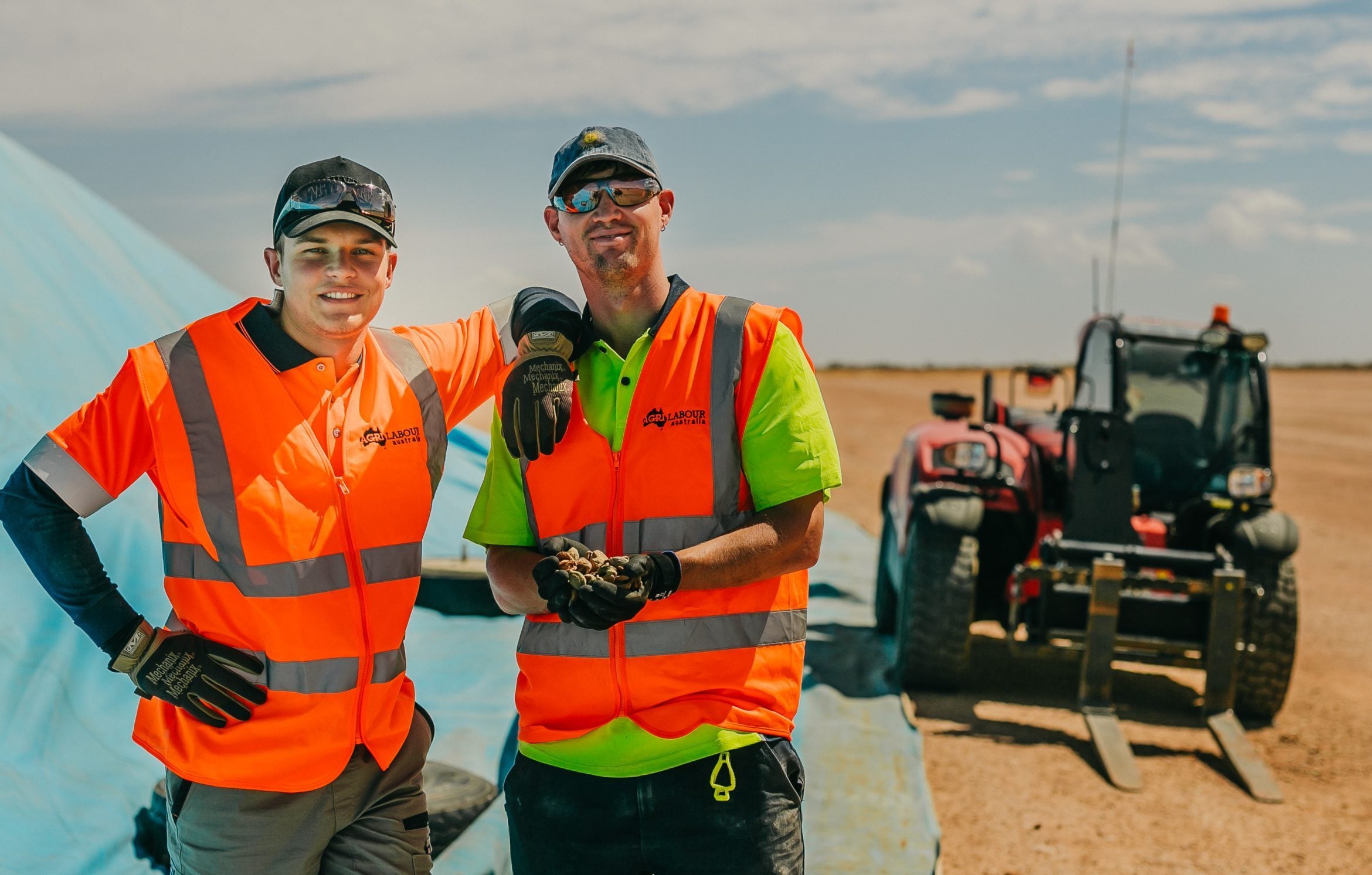 Team on site wearing high visibility clothing with a telehandler behind them